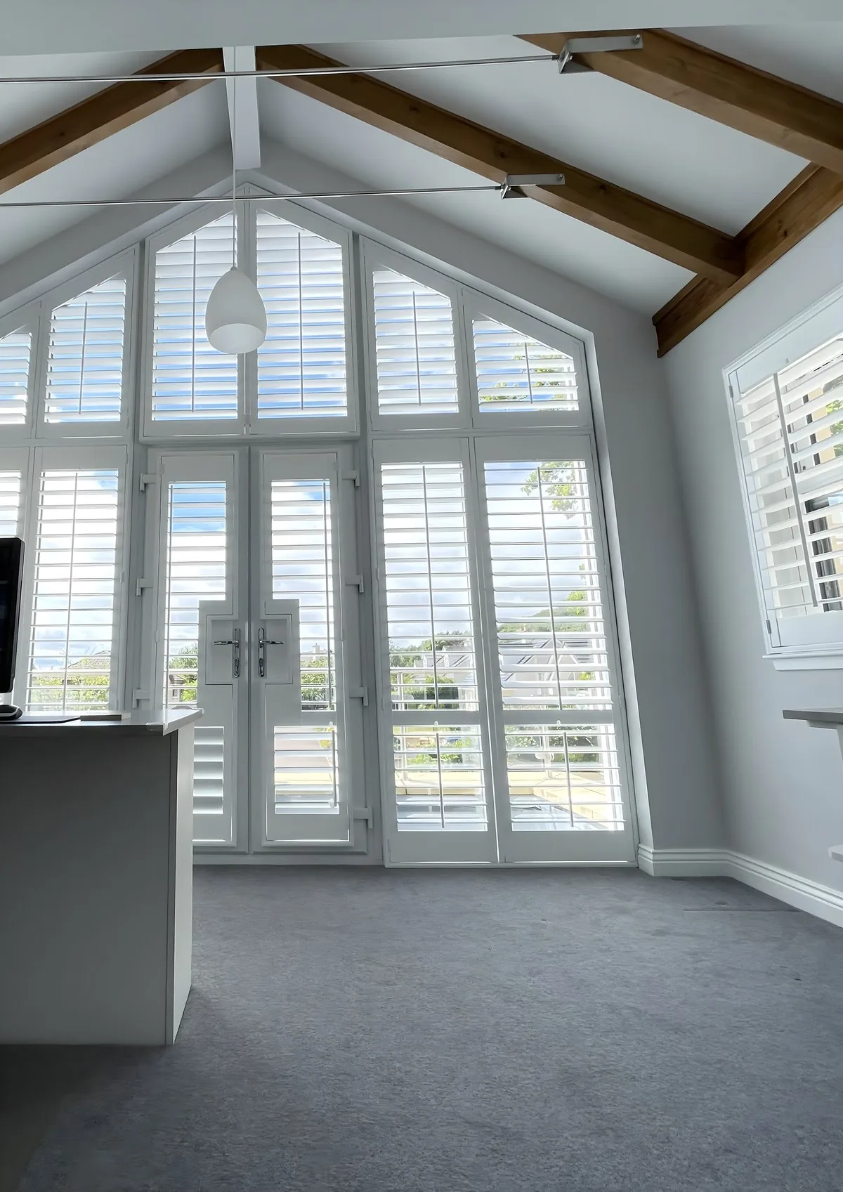 White full height shutters installed on a large living room window
