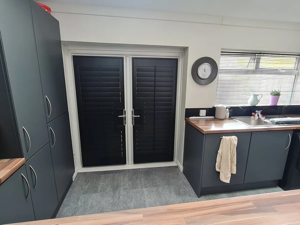 Black full height shutters on French doors in a modern kitchen