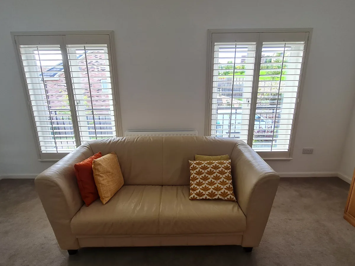 Full height shutters in a modern living room with grey sofa